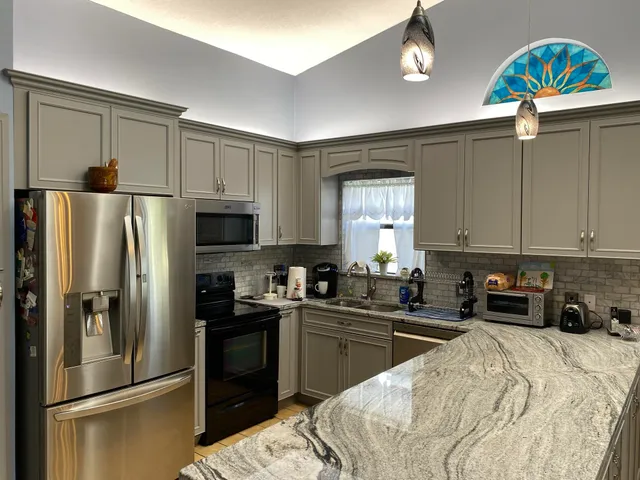 a kitchen with granite countertop a refrigerator stove and microwave