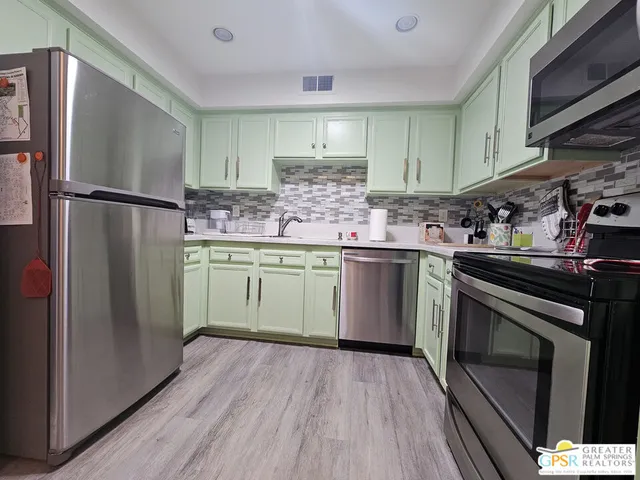 a kitchen with stainless steel appliances a sink cabinets and a wooden floor