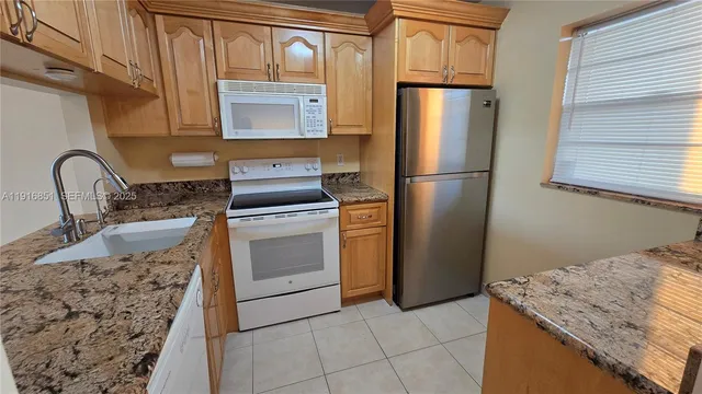 a kitchen with granite countertop a sink stove and refrigerator