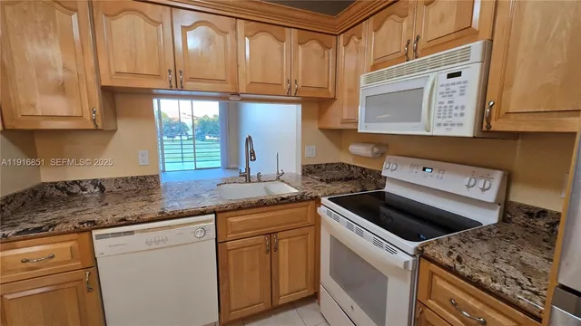 a kitchen with granite countertop a sink stove and cabinets