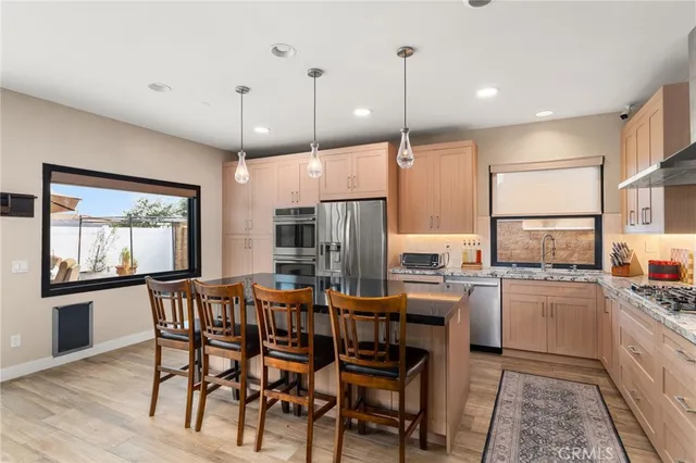 a kitchen with stainless steel appliances granite countertop table chairs stove and refrigerator