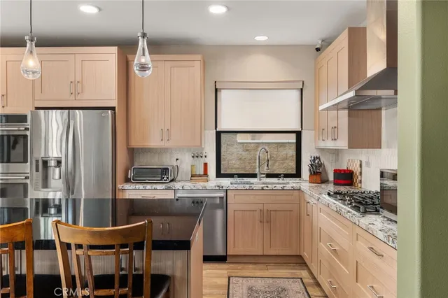a kitchen with stainless steel appliances a stove top oven a refrigerator a sink and dishwasher