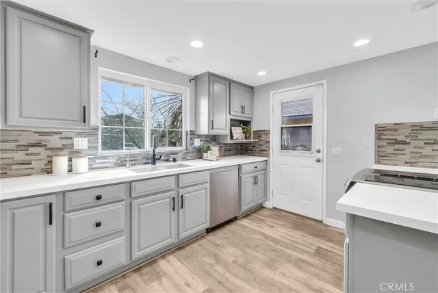 a kitchen with sink stove and white cabinets with wooden floor