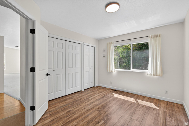 380 Luzern Road Midway, UT 84049 - Photo 26 of 74 Room featuring wood-finish flooring, a large window, a ceiling-mounted light fixture, and two bi-fold door closets
