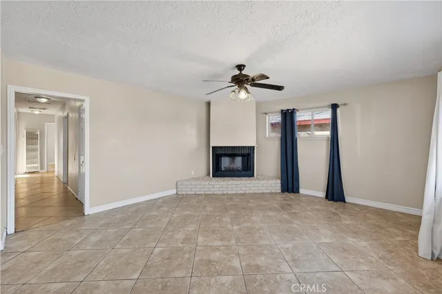 a view of an empty room with a fireplace and a chandelier fan