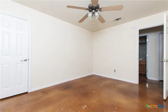 an empty room with a ceiling fan and wooden floor