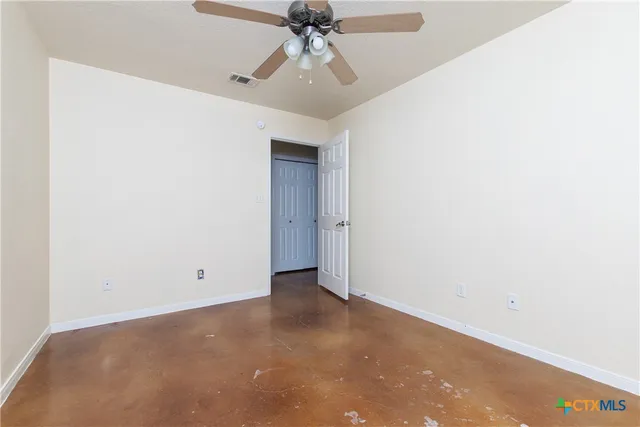 an empty room with a ceiling fan and carpet