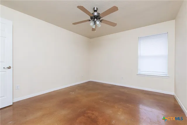 an empty room with a window and a ceiling fan
