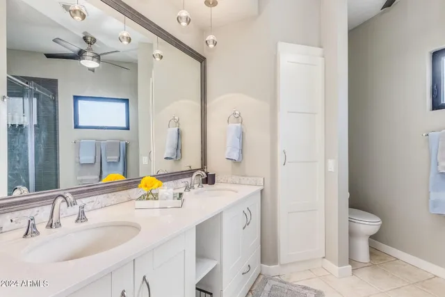 a bathroom with a sink double vanity granite and a toilet