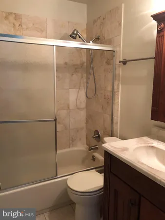 a bathroom with a granite countertop bathtub shower sink vanity and toilet