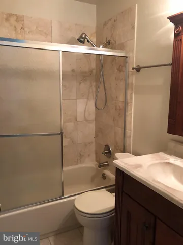 a bathroom with a granite countertop bathtub shower sink vanity and toilet