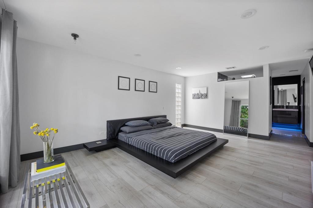 4134 Travis Street, Unit 11 Dallas, TX 75204 - Photo 17 of 29 a spacious bedroom with a bed and wooden floor