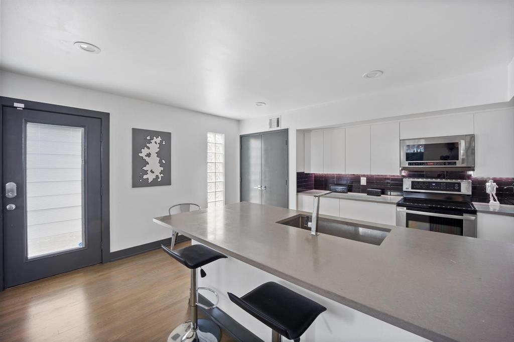 4134 Travis Street, Unit 11 Dallas, TX 75204 - Photo 5 of 29 a kitchen with stainless steel appliances wooden floor and a refrigerator