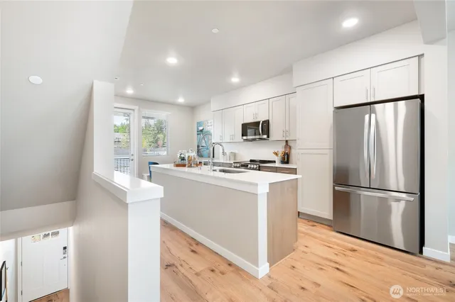 a kitchen with a refrigerator a microwave oven a sink and cabinets
