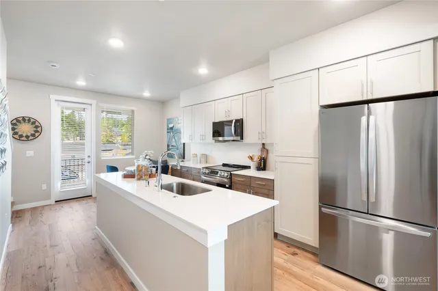 a kitchen with stainless steel appliances a refrigerator a sink a stove a microwave a center island and furniture