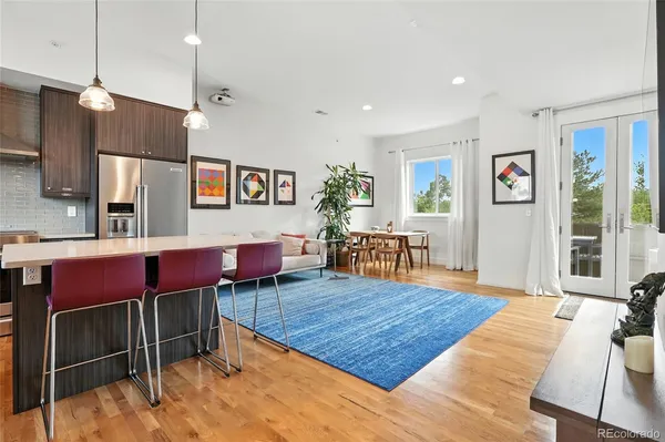 a living room with furniture kitchen view and a wooden floor