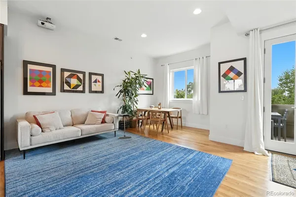 a living room with furniture and painting on the wall with wooden floor