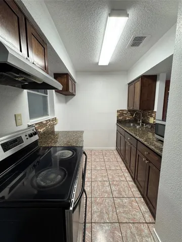 a kitchen with granite countertop a refrigerator and a stove