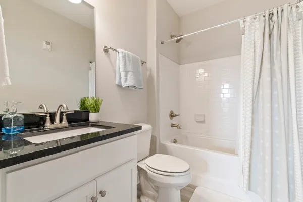 a bathroom with a granite countertop sink a toilet a mirror and shower