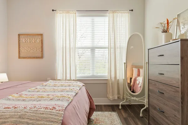 a bedroom with a bed a dresser and windows