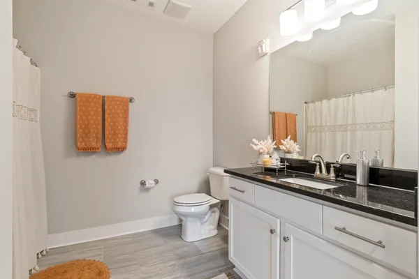a bathroom with a granite countertop sink a toilet and a mirror