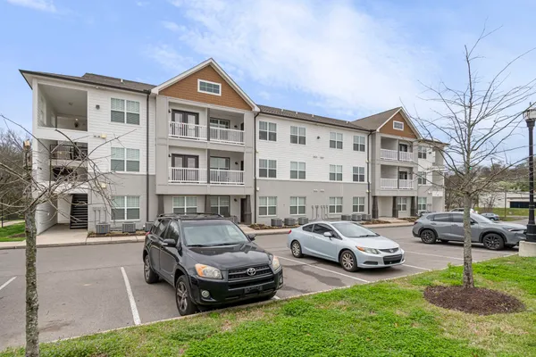 a car parked in front of a brick building next to a yard