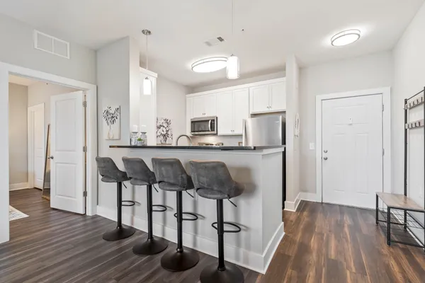 a kitchen with kitchen island granite countertop a table chairs refrigerator and microwave