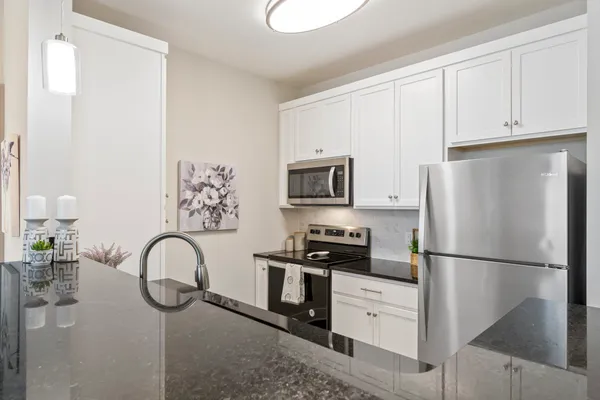 a kitchen with stainless steel appliances granite countertop a refrigerator a stove and a sink with wooden floor