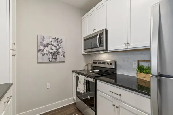 a kitchen with white cabinets and black appliances