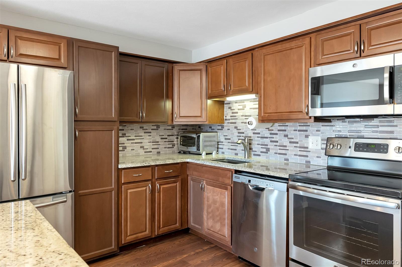 a kitchen with stainless steel appliances granite countertop a refrigerator stove a sink and dishwasher with wooden cabinet