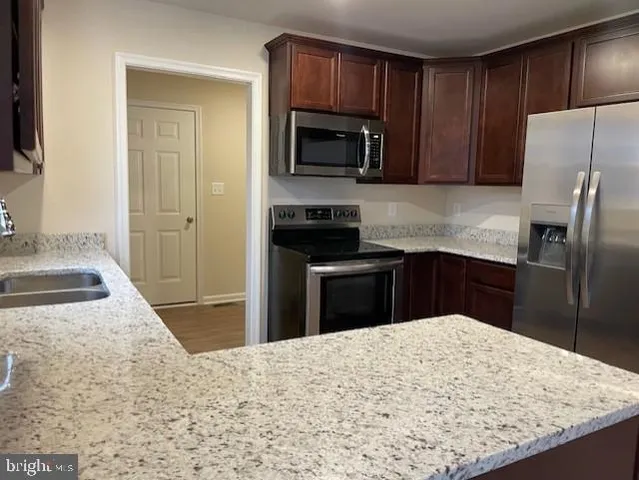a kitchen with granite countertop wooden cabinets a refrigerator and a sink
