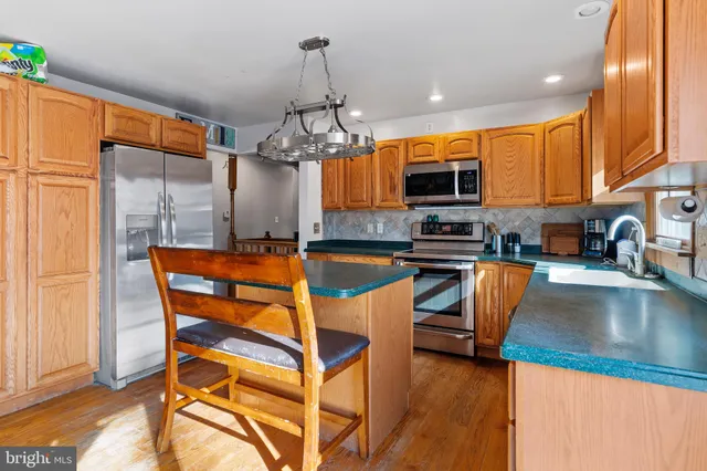 a kitchen with stainless steel appliances granite countertop a stove top oven a sink dishwasher a dining table and chairs with wooden floor