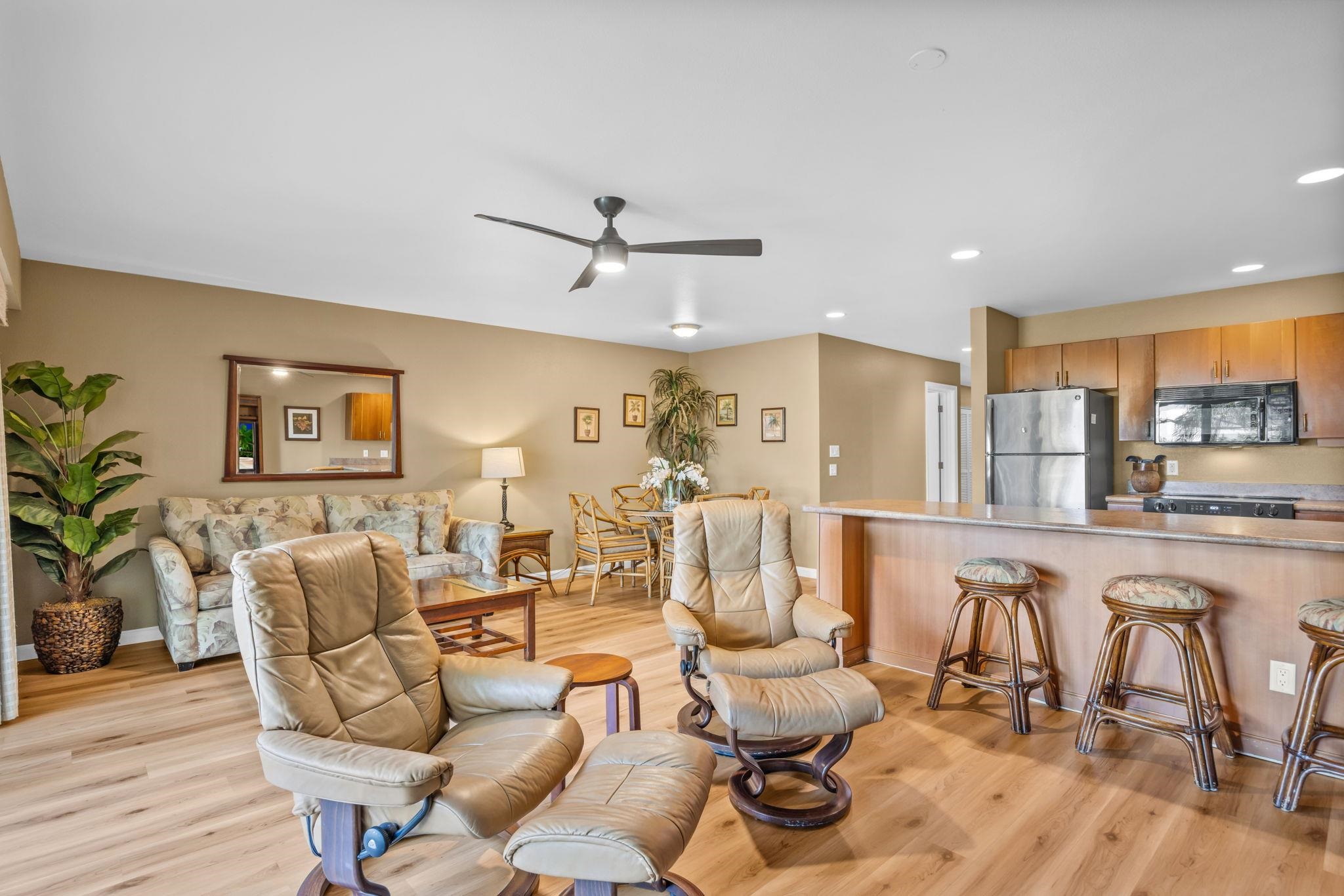 a living room with furniture kitchen view and a wooden floor