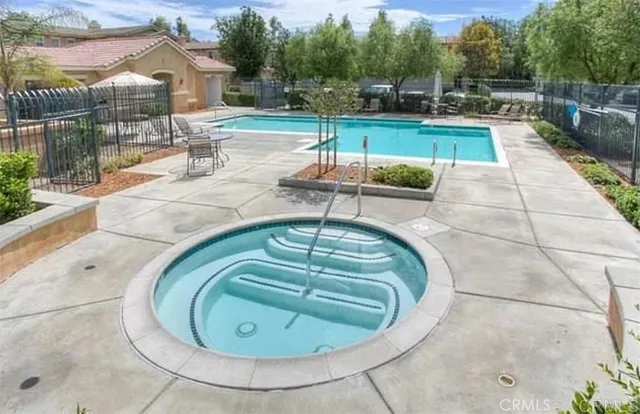 a swimming pool with outdoor seating and covered with trees