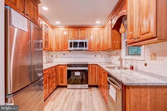 a kitchen with stainless steel appliances granite countertop a stove a sink and a refrigerator