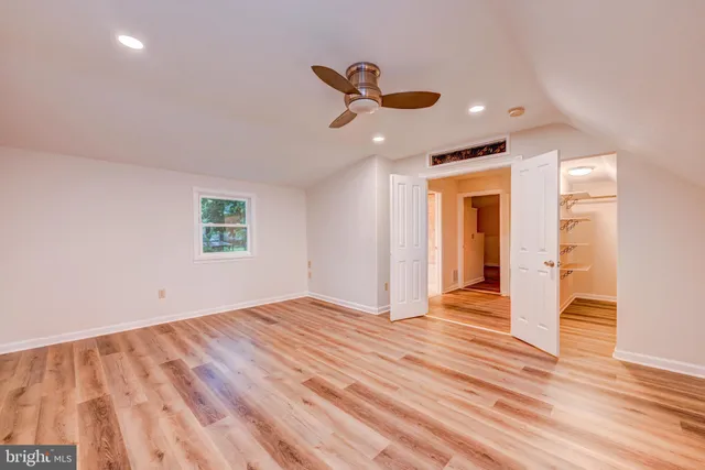 a view of empty room with wooden floor and fan
