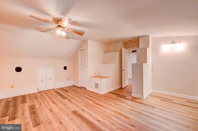 a view of empty room with wooden floor and fan