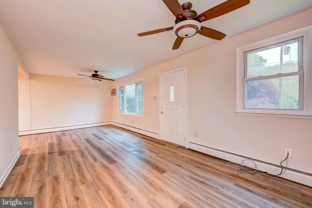 a view of empty room with wooden floor and fan