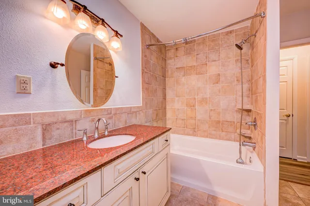 a bathroom with a granite countertop sink a mirror a bathtub and shower