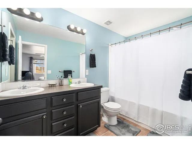 a bathroom with a double vanity sink toilet and mirror