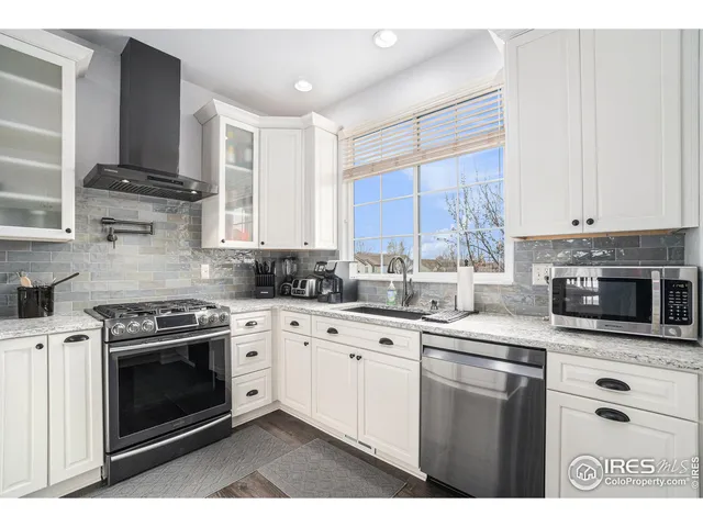 a kitchen with stainless steel appliances granite countertop a stove a sink and white cabinets