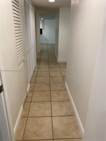 a view of a hallway with wooden floor and a bathroom