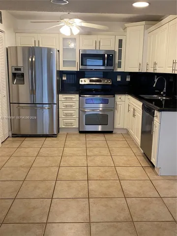a kitchen with stainless steel appliances kitchen island granite countertop a refrigerator and a stove top oven