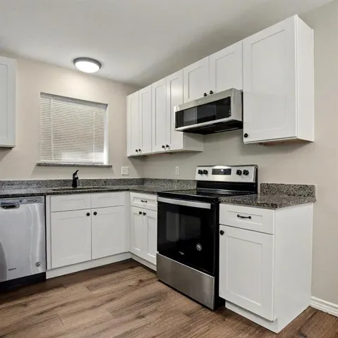 a kitchen with stainless steel appliances granite countertop a stove a white cabinets and a granite counter tops