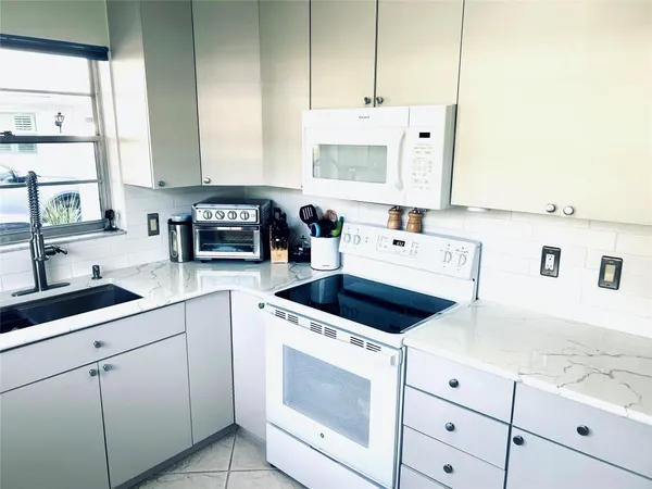 a kitchen with cabinets appliances a sink and a window