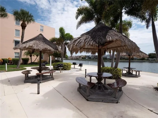 a view of a patio with dining table and chairs under an umbrella with a fire pit and barbeque grill