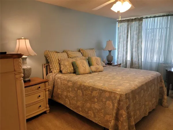 a bed sitting in a bedroom next to a lamp and window
