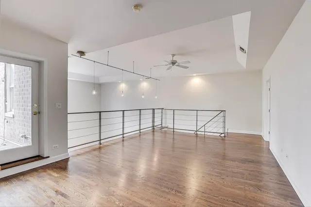 an empty room with wooden floor fan and windows