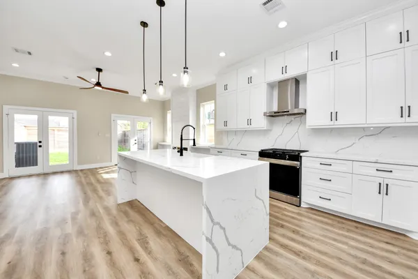 a large white kitchen with kitchen island white cabinets and stainless steel appliances