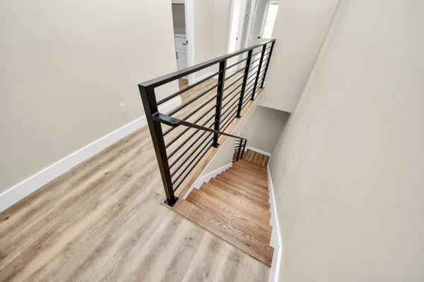 an empty room with wooden floor ceiling fan and windows